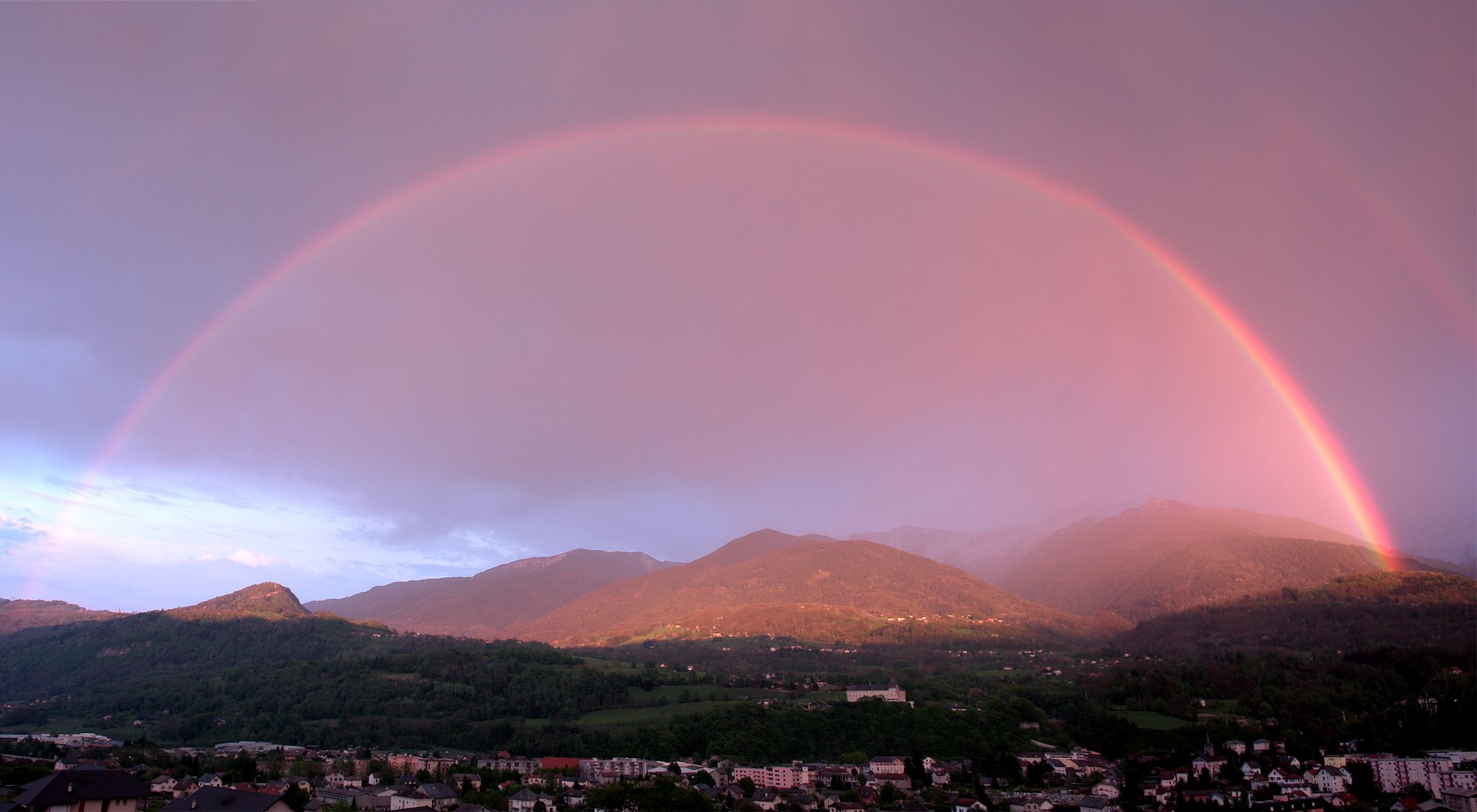 A rainbow breaking over an Alpine valley after a spring storm
